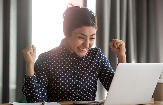 Excited young indian student receiving notification about hiring to work or unexpected good news. Happy successful female employee celebrating victory win achievement or job promoting.